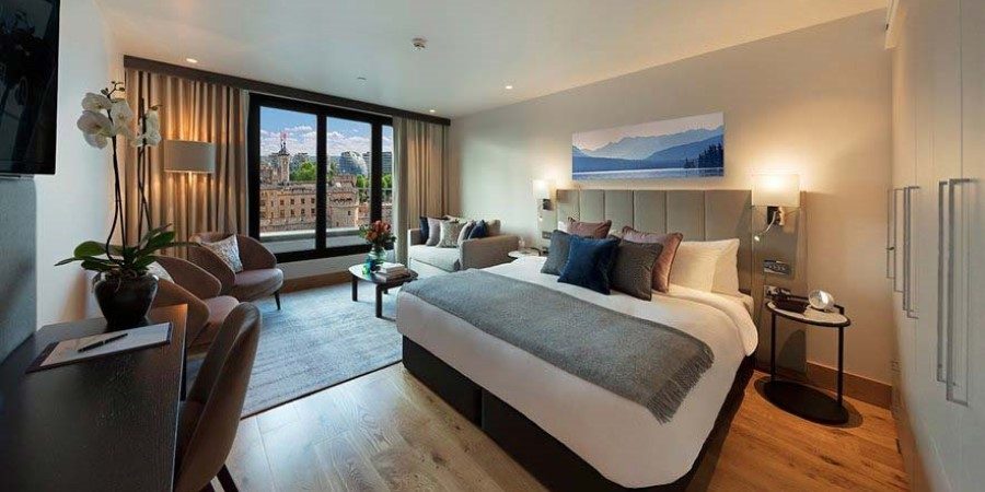 Elegant hotel room showcasing a large bed and a beautiful city view visible through the window.